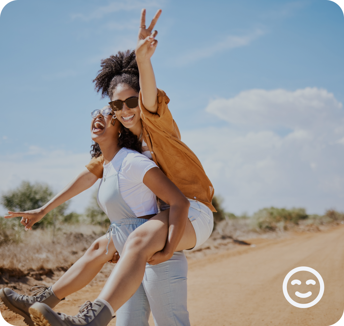 A woman riding piggyback on her friend and showing a peace sign